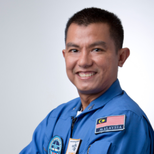 Headshot of Captain Faiz Kamaludin, Malaysian Astronaut wearing his astronaut uniform and smiling at the camera.